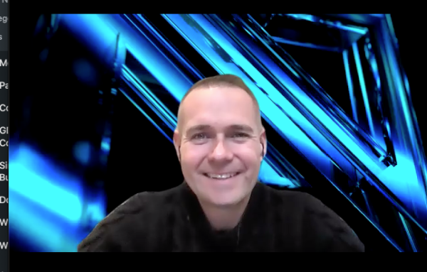 MetaVRse Co-founder Alan Smithson smiles against blue-and-black electric MetaVRse logo background