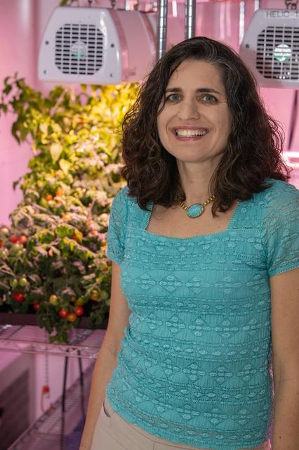 Dr. Gioia Massa smiles as she stands near an outdoor setting with a blooming plant in the background