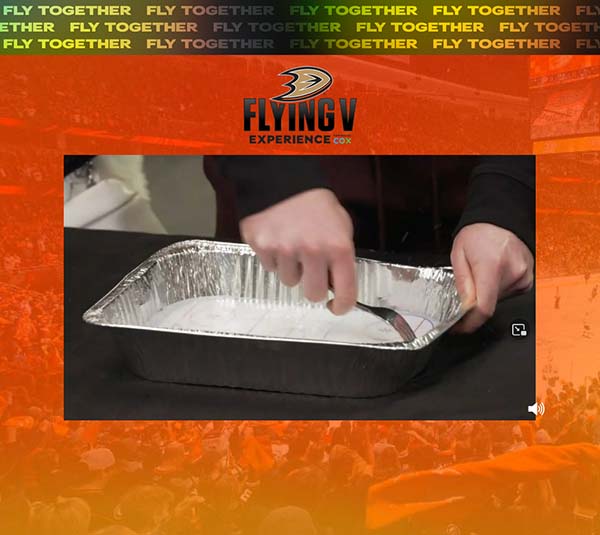 Jamie's hands closeup as he uses a fork to scratch a sheet of ice in a disposable aluminum pan