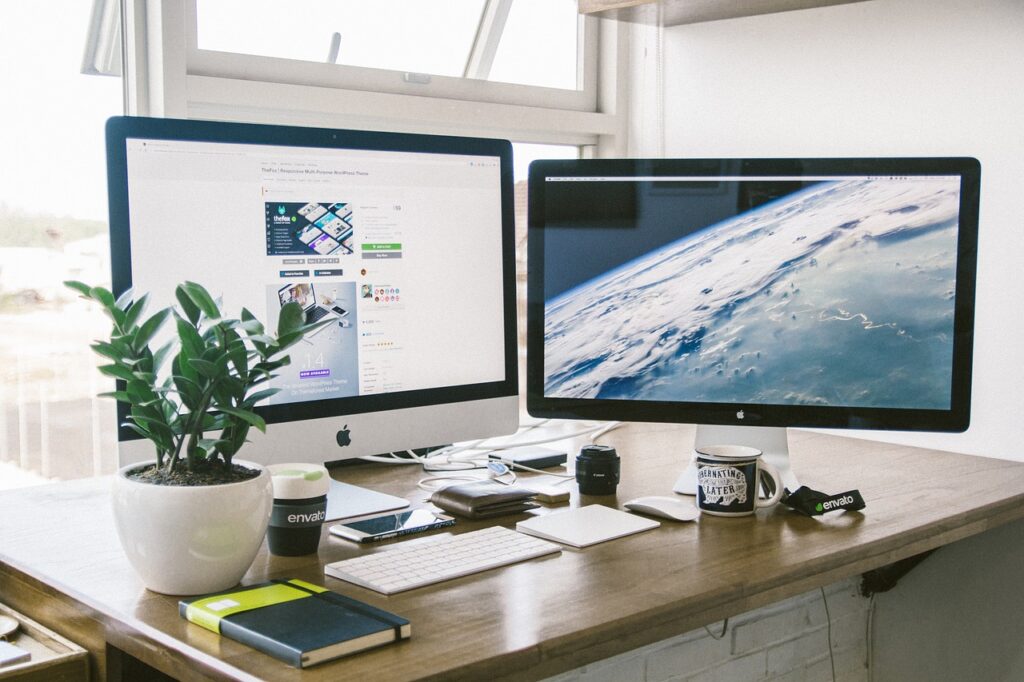 Two computer screens next to a window in an upscale office setting