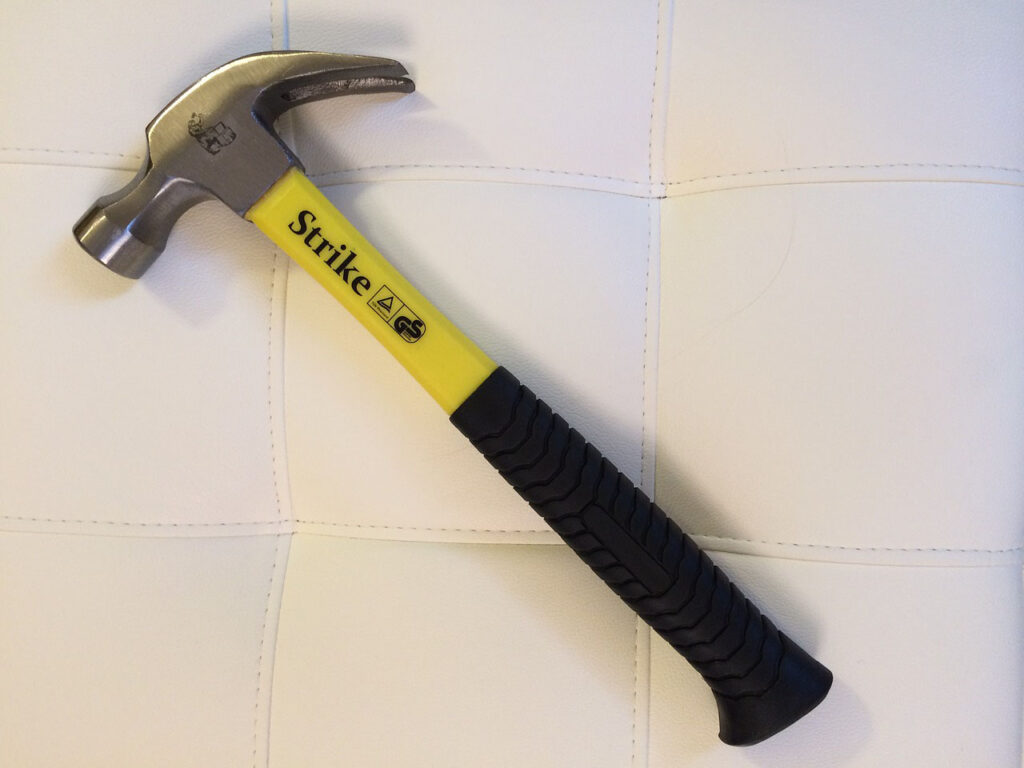 Claw hammer with a yellow handle against a white quilted background