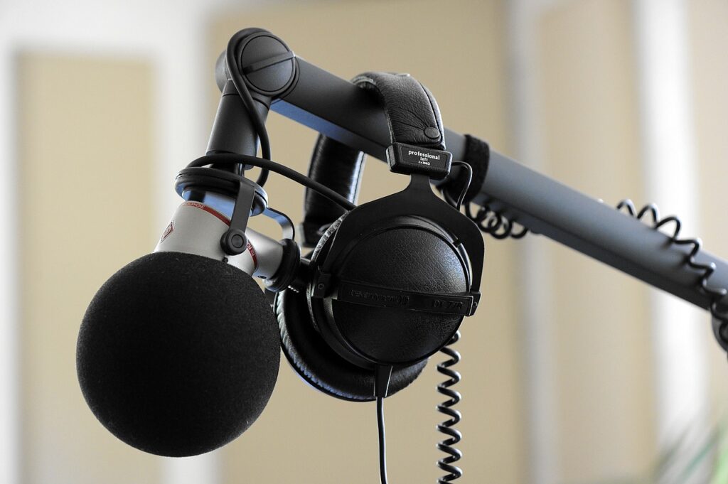 Headphones hang over a boom on which a blue mic is fixed