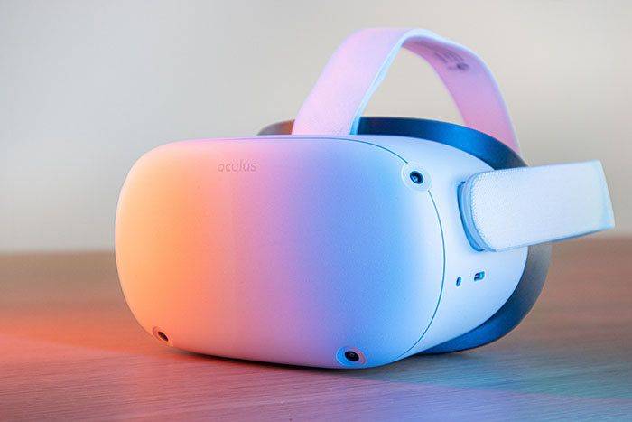 Closeup of white virtual reality headset in multicolored lights as it sits on a desk
