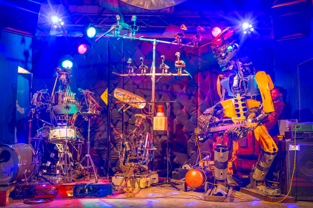 One Love Machine Band, comprised of robot drummer, "band manager" Sir Elton Junk, robot bass player and robotic birds, onstage.