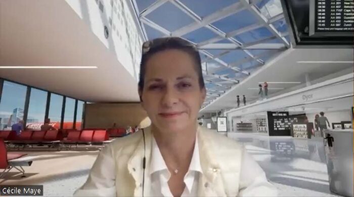 AckTao CEO/Co-Founder Cecile Maye smiles against the Zoom background of one of her digital scenarios: an airport.