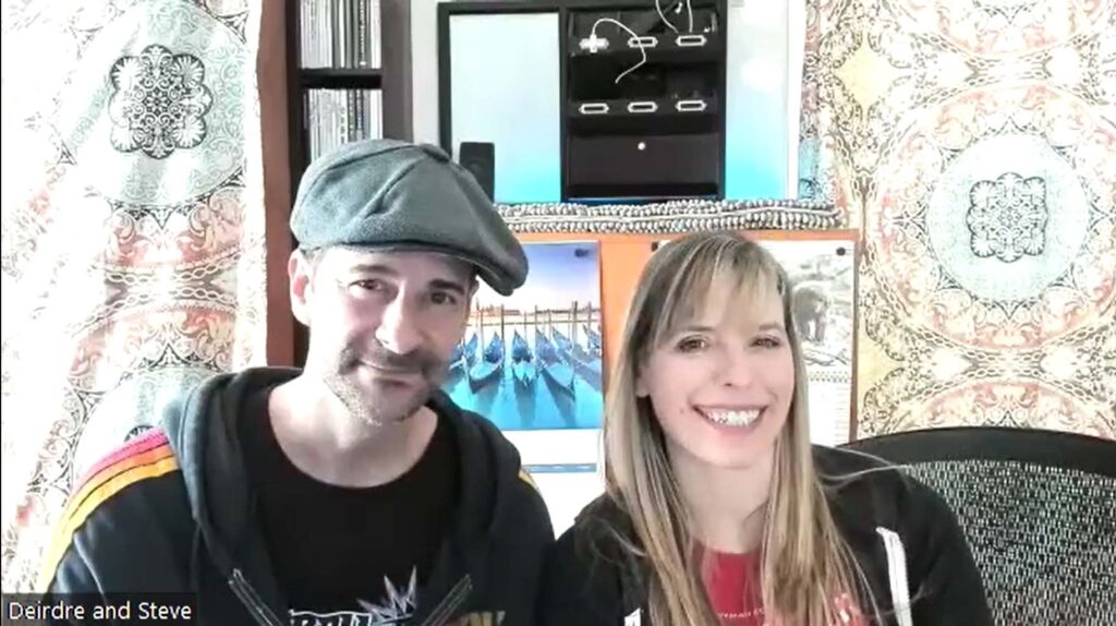 Ferryman Collective founding members Stephen Butchko and Deirdre V. Lyons smile as they sit in front of a curtain background with several photographic prints