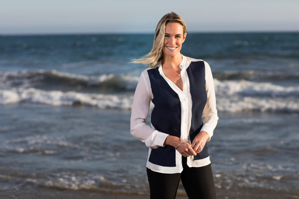 Journalist and adventurer Ashlan Cousteau smiles as she stands near the ocean.