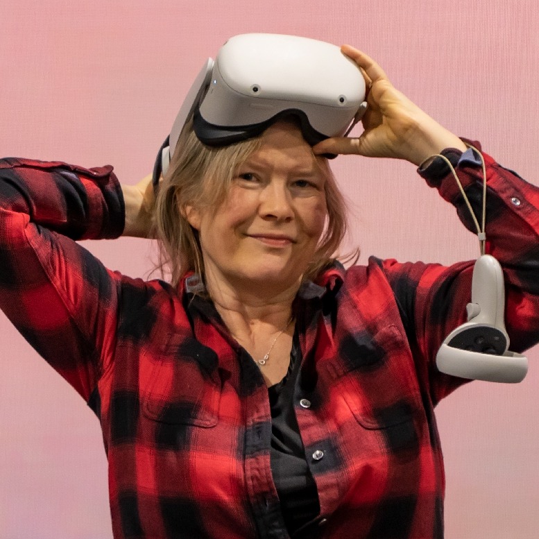 Author Helen Lundstrom Erwin smiles as she wears a white VR headset on her head.