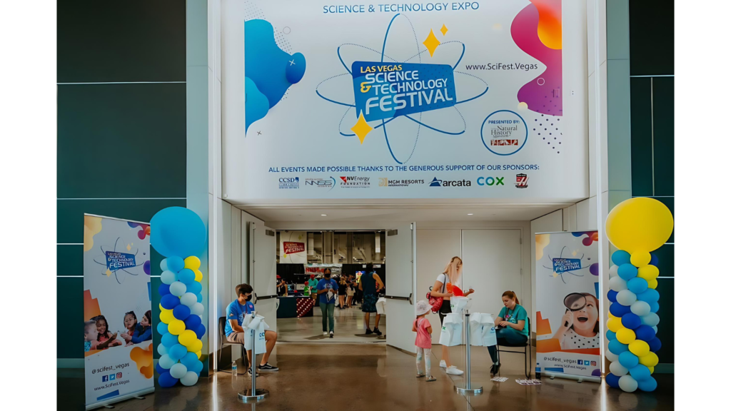 Parent and child turn in tickets outside a building iwth "Las Vegas Science and Technology Festival" on a white banner over the door.