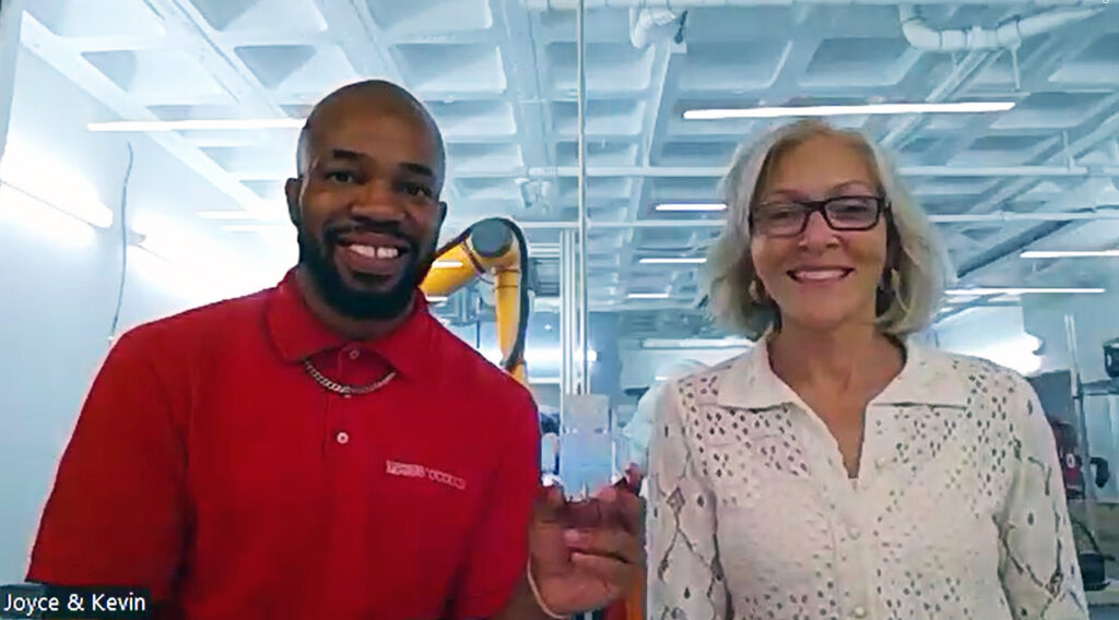 MassRobotics STEM Program Manager Kevin Smith and MassRobotics Co-Founder/Chief of Operations Joyce Sidopoulos smile and Kevin holds up a miniature robot as they discuss RoboBoston and robotics education from MassRobotics' lab.