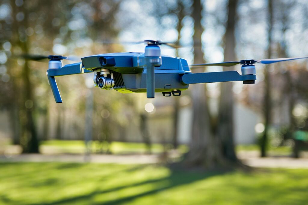 Blue drone flies in a park setting.