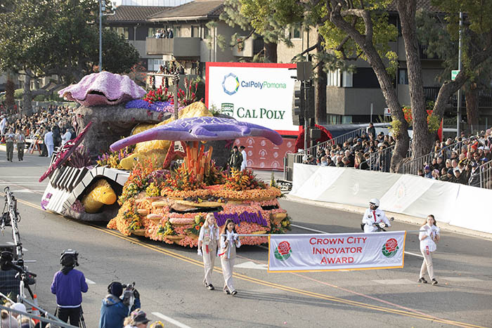 Cal Poly Universities float, "Shock N' Roll", in the Rose Parade on January 1, 2024, with the "Crown City Innovator" award banner before it, carried by outwalkers.