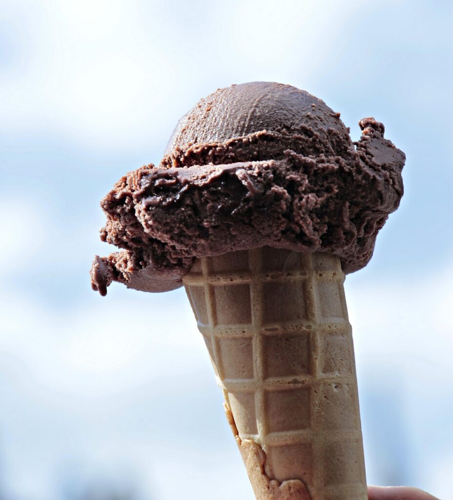 Chocolate ice cream cone silhouetted against a blue sky