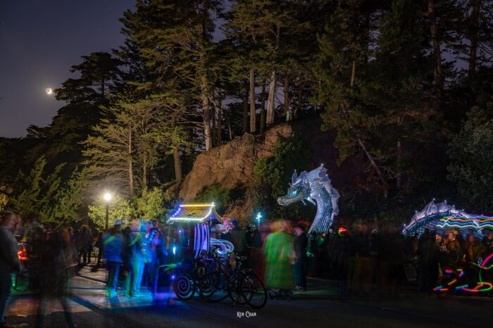 Naga, lit up at night, presides majestically over Rainbow Falls pond with a full moon in the distance.