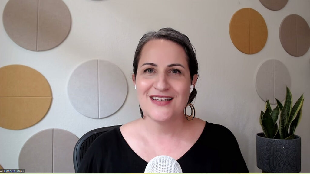 Innovator, human-centric AI consultant and Cake on Tuesday author/podcast host Elizabeth Bieniek smiles against a white Zoom background with silver and gold circles.