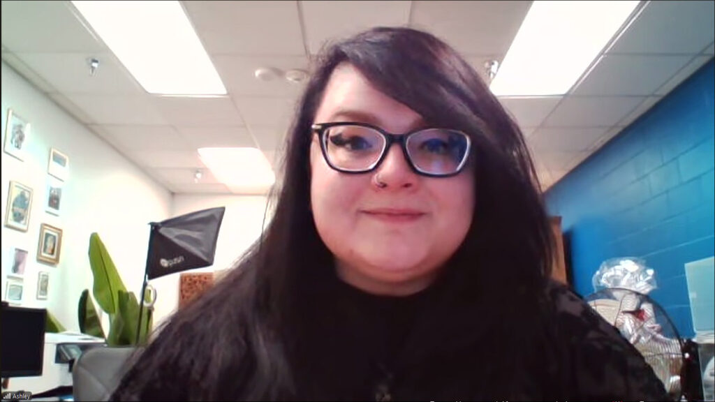 Las Vegas Science and Natural History Museum Marketing Manager Ashley Glenn smiles against a flourescently-lighted museum room background.