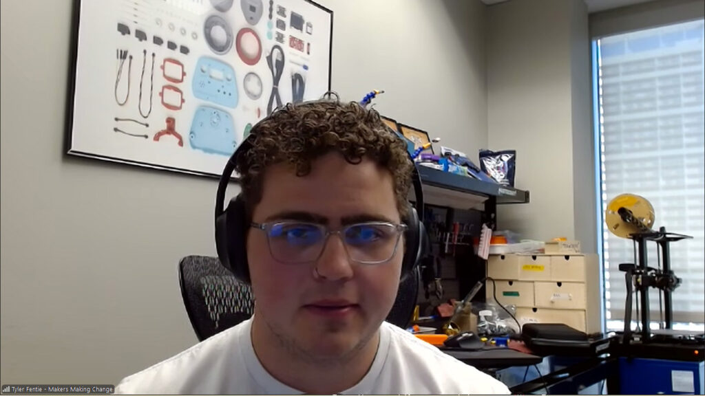 Neil Squire Society Makers Making Change Adaptive Gaming Lead Tyler Fentie. wearing headpohnes, smiles against an office background with a poster of assistive technologies makers can create.