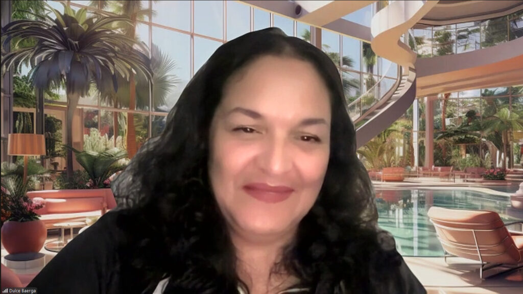 Futurist and artist Dulce Baerga, creator of Avatar Gods, smiles against a Zoom background.