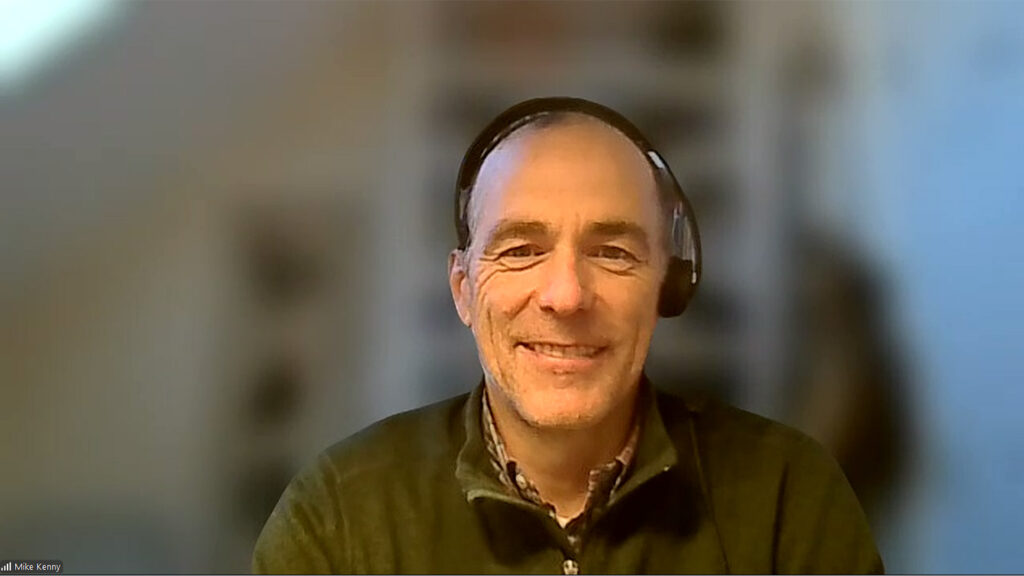 MathFactLab creator and company owner Mike Kenny smiles against a blurred Zoom background of white bookcases.