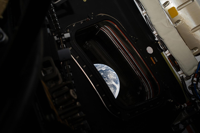 Earth is seen through the window of the Orion spacecraft, "Integrity", as it orbits the Moon.