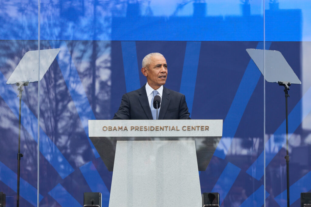 President Obama speaks from behind a white lectern with the words "Obama Presidential Center" during the Center's Grand Opening.