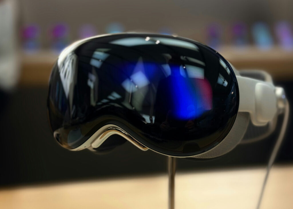 Blue and purple light reflect in the lenses of a headset sitting on a stand.